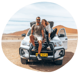Geländewagen mit jungem Paar auf der Motorhaube in der Wüste stehend